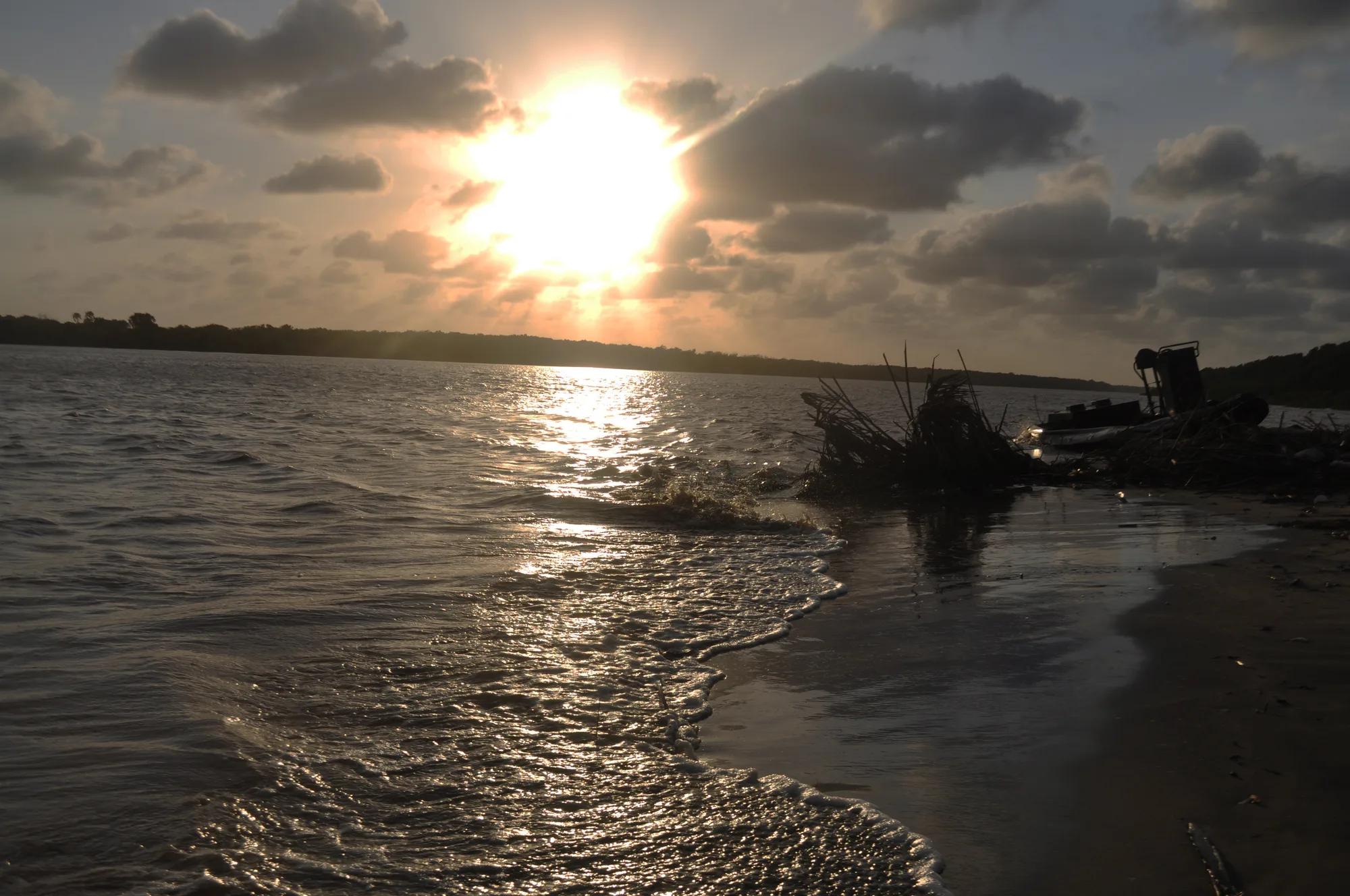 A wide river bend at sunset, low light on the water and dark trees along the bank.